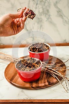 Cherry crumble with chocolate granola served served in portioned red plates..The process of eating. In the hands of a young woman