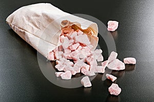 Cherry flavored sugar chunks in bag on black background photo