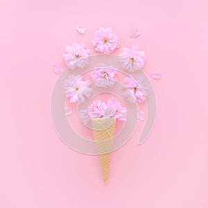 Cherry flowers in a ice cream waffle cone on pink background