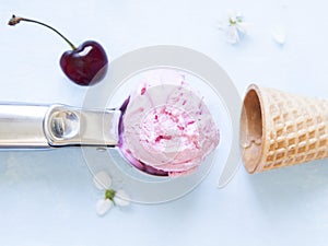 Cherry ice cream scoop in spoon, empty sugar cone, cherry berry and flowers