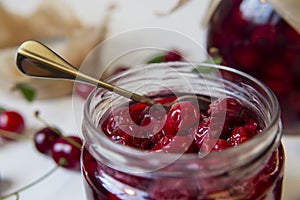 Cherry jam in a glass jar. Whole cherries without pits.