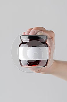 Cherry Jam Jar Mock-Up. Blank Label - Male hands holding a jam jar on a gray background