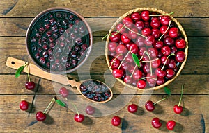 Cherry jam and red cherries in a basket on a wooden table.