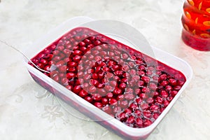 Cherry jelly dessert with fresh berries in square food container