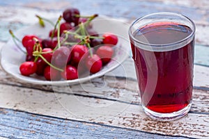 Cherry juice with cherries in plate on turquoise table