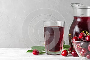 Cherry juice in a glass and jug with fresh berries on white background. Refreshment summer drink