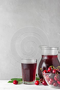 Cherry juice in a glass and jug with fresh berries on white background. Refreshment summer drink. Healthy drink