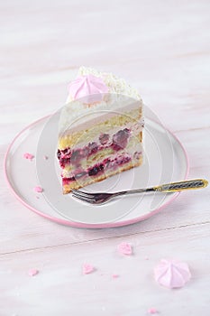 Cherry Layer Cake decorated with fine coconut flakes and colored meringue cookies