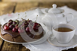 A cherry pie, with fresh cherries a cup of tea and a kettle