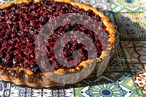 Cherry pie top view. Homemade baking. Round open tart with filling. Pouring pastries on the table of colored tiles