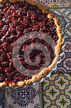 Cherry pie top view. Homemade baking. Round open tart with filling. Pouring pastries on the table of colored tiles