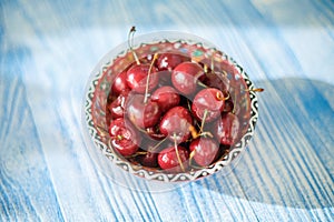 Cherry on plate on blue wood background