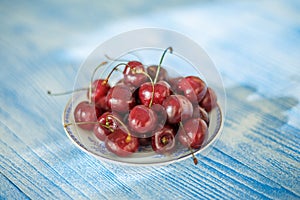 Cherry on plate on blue wood background