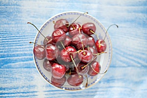 Cherry on plate on blue wood background