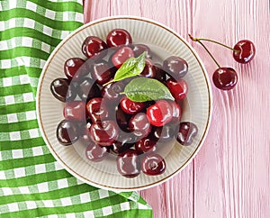 Cherry in a plate organic tasty summer on a pink wooden background, towel