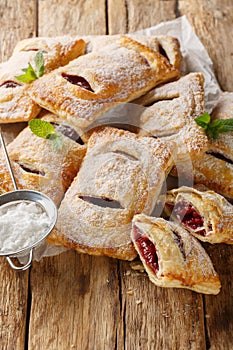 Cherry puff pastry with powdered sugar and mint close-up. Vertical