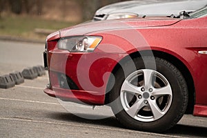 Cherry red car front detail with big light-alloy wheel