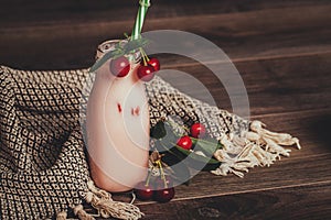 Cherry smoothie or milkshake in jar with fresh cherries on wooden background