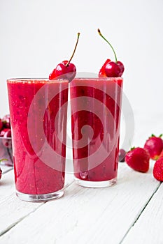 Cherry smoothie and tasty berries on white table. Fresh tasty milkshake