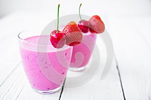 Cherry, strawberry milkshake and tasty berries on white table. Delicious cocktail