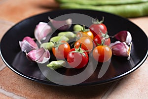 cherry tomato, broad beans and garlic in black dish