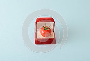 Cherry tomatoe in an  engagement ring box. on a cream background. The concept of marriage and engagement. Romantic lifestyle idea.