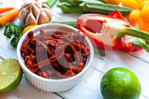 Cherry tomatoes with bell peppers gloves and vegetables greens and  on the white wooden background table