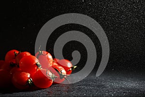 Cherry tomatoes on a black background in the spray
