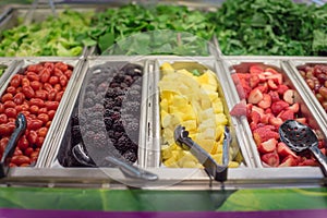 Cherry tomatoes, blackberries, pineapple chunks, strawberry, red grape trays at salad bar in USA