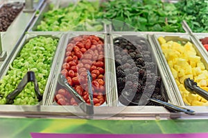 Cherry tomatoes, blackberries, pineapple chunks, strawberry, red grape trays at salad bar in USA