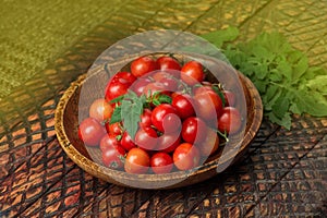 Cherry tomatoes in the bowl on dark wooden background