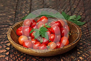 Cherry tomatoes in the bowl on dark wooden background