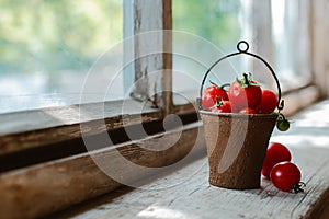 Cherry tomatoes in a decorative rusty old bucket on a dark rustic background