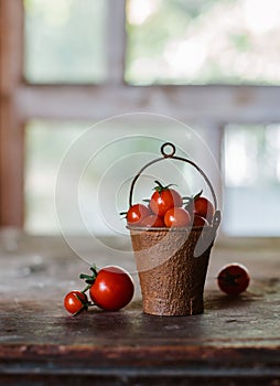 Cherry tomatoes in a decorative rusty old bucket on a dark rustic background.