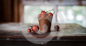 Cherry tomatoes in a decorative rusty old bucket on a dark rustic background.