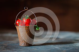 Cherry tomatoes in a decorative rusty old bucket on a dark rustic background