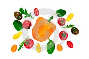 Cherry tomatoes of different colors, arugula leaves and basil around a bell orange pepper isolated on white