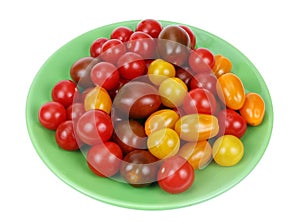 Cherry tomatoes of different colors on a green plate isolated
