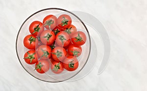 Cherry tomatoes in the glass bowl on the marble table texture