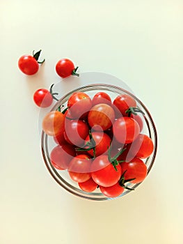 Cherry tomatoes in a glass cup, on a white background.