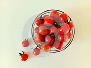 Cherry tomatoes in a glass cup on a wooden background