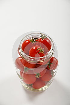 Cherry tomatoes in glass jar over white