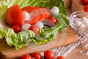 Cherry tomatoes, green cabbage, white feta cheese, cooking, salad on a wooden table and cutting board