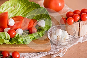 Cherry tomatoes, green cabbage, white feta cheese, cooking, salad on a wooden table and cutting board