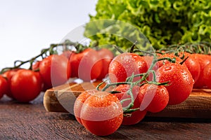 Cherry tomatoes and lettuce leaves with water drops on wood in rustic wood table, white background, selective focus