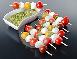 Cherry tomatoes and mozzarella on skewers and a vinaigrette sauce with basil