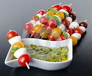 Cherry tomatoes and mozzarella on skewers and a vinaigrette sauce with basil