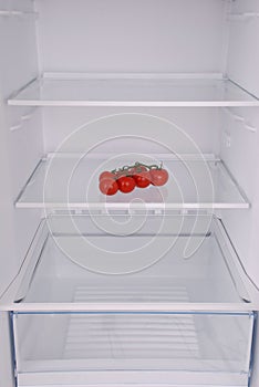 Cherry tomatoes in open empty refrigerator.