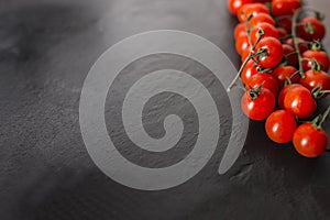 Cherry tomatoes over a black stone plate with copy space.