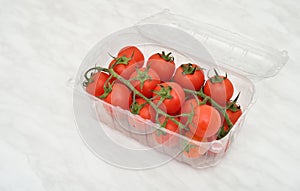 Cherry tomatoes in plastic container on the marble table texture